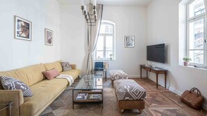A living room with a sofa, ottoman, coffee table, and a flat-screen TV. - Authentic Restored Apt In The Old City (Tel Aviv-Yafo)