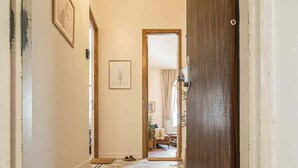 A hallway with a patterned floor, a wooden door, and a light fixture. - Authentic Restored Apt In The Old City (Tel Aviv-Yafo)