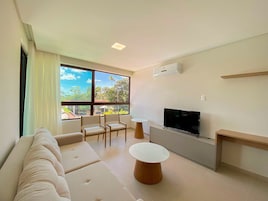 Una sala de estar moderna con sofá, televisor y comedor.