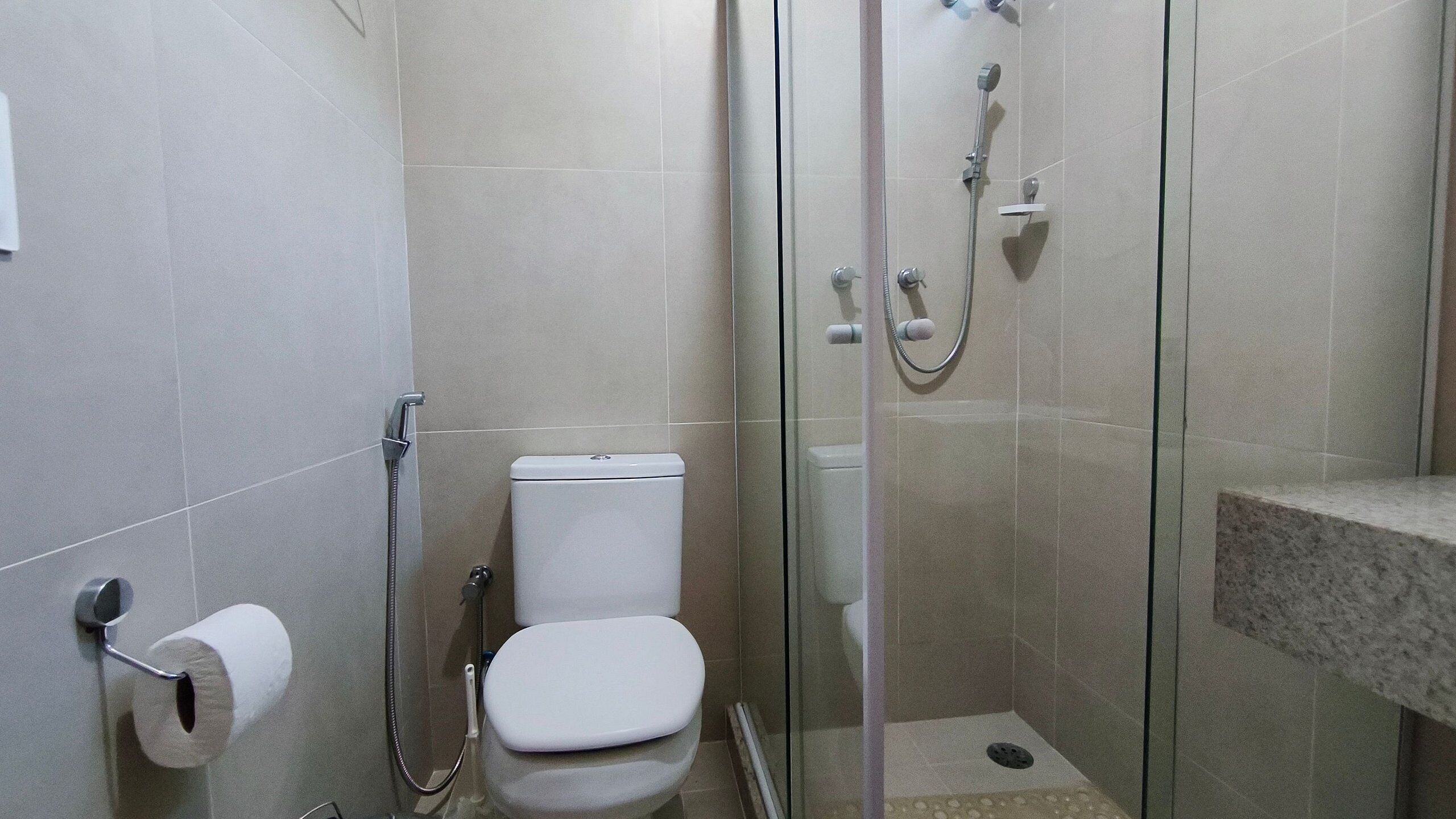 A bathroom with a toilet, a shower, and a sink.