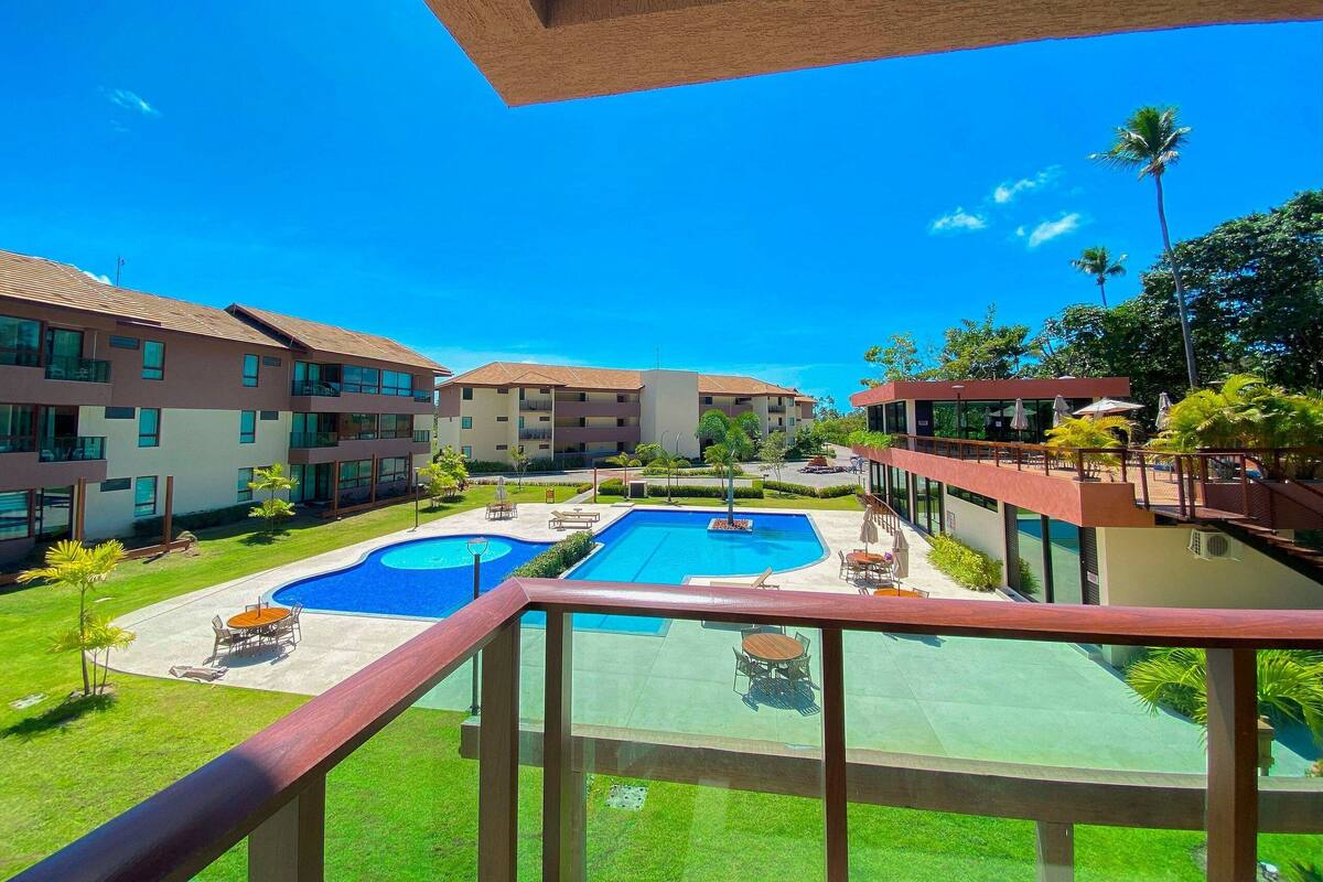 Un hotel con piscina, mobiliario exterior y un cielo azul despejado.