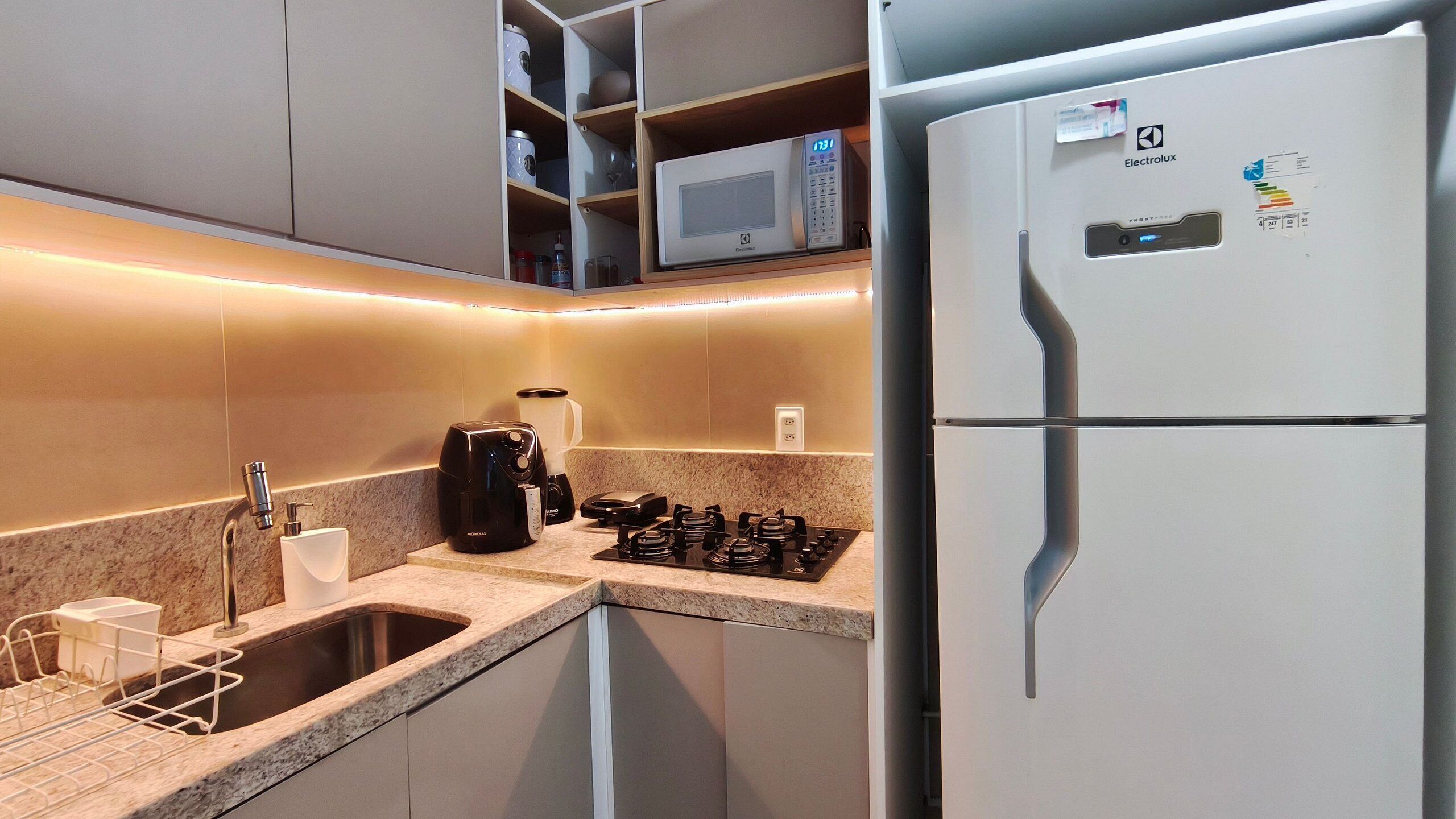 A compact kitchen with a built-in microwave, a refrigerator, a gas stove, and a coffee maker.