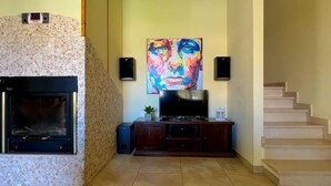 A living room with a fireplace, a flat-screen TV, a painting, and a staircase. - ⭑ ⭑ ⭑ ⭑ Elegant apartment with whirlpool and gymnasium (Silvi)