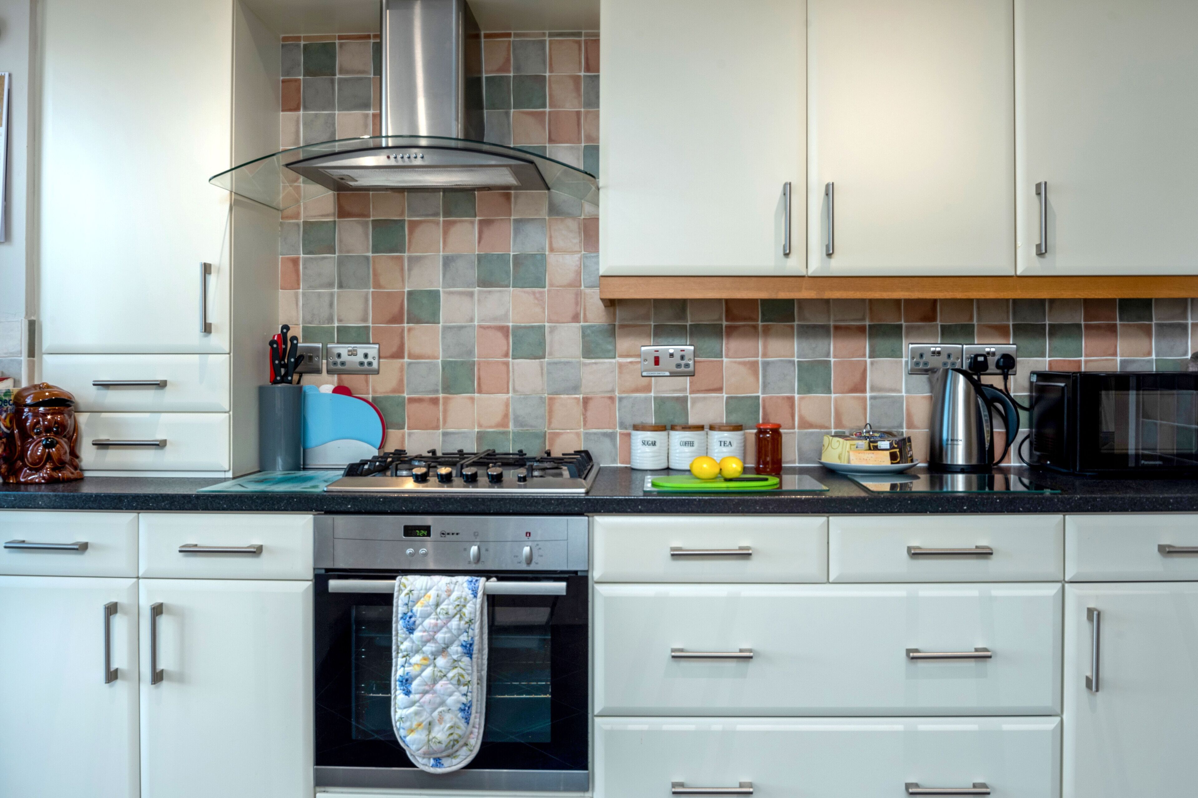 A modern kitchen with white cabinets, a gas stove, an oven, and a microwave.