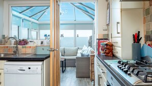 Una cucina moderna con lavastoviglie, fornelli e zona pranzo con divano e tavolo.