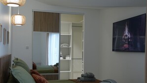 Quarto com cama, almofadas, mesa de cabeceira com toalhas, guarda-roupa e um quadro na parede.