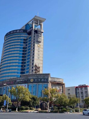 A multi-story hotel with a prominent curved facade, signage indicating it is a hotel, and a clear sky above.