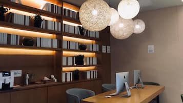Uma biblioteca moderna com estantes, máquina de café e computadores Apple iMac.