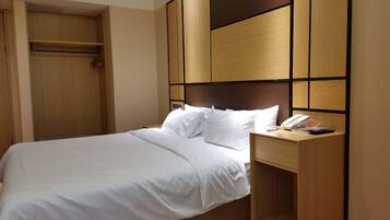Quarto de hotel com cama, mesa de cabeceira e guarda-roupa.