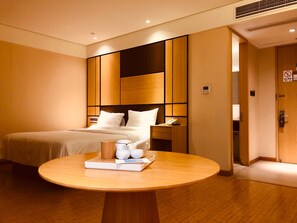 A hotel room with a bed, bedside table, and a round table with a tray of items.