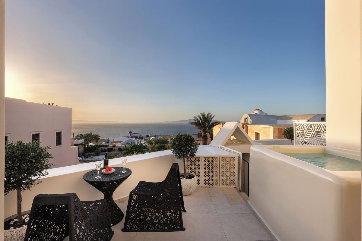 Un balcón con mesa y sillas, una piscina pequeña y vistas al mar y edificios.