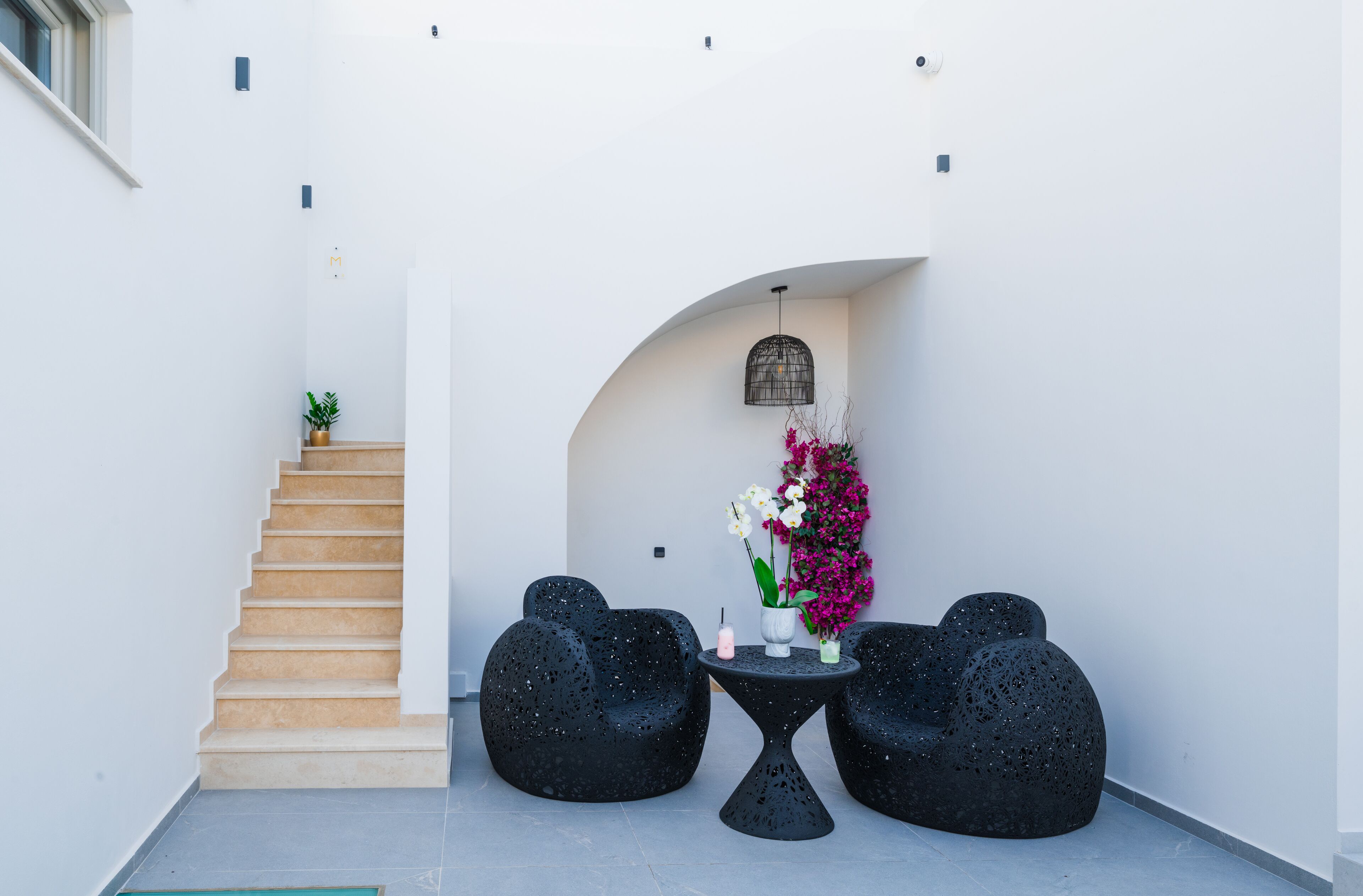 A modern interior with a staircase, black seating, and a floral arrangement.
