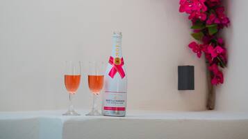 A bottle of Moët & Chandon champagne and two glasses on a white surface against a wall with pink flowers.