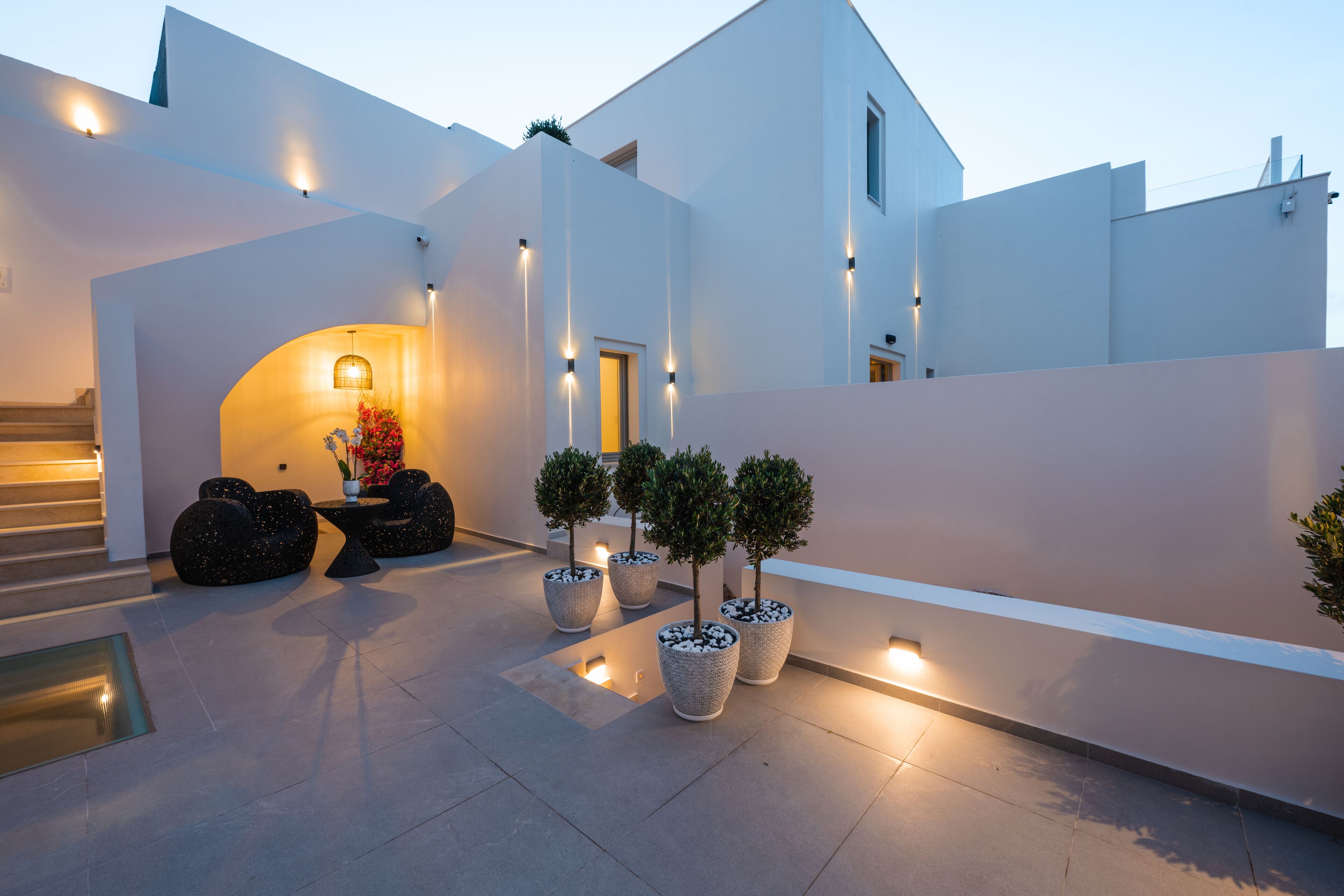 A modern building with a white exterior, a staircase, and potted plants.