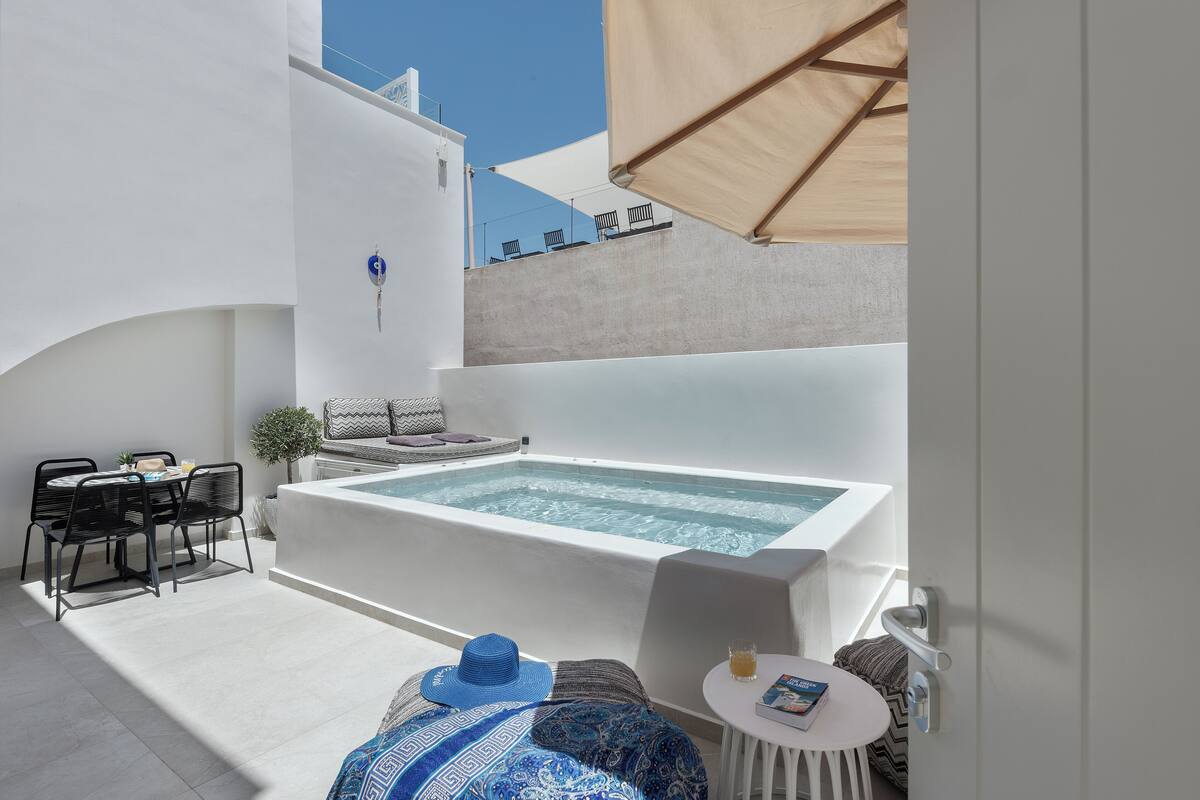 Un espacio exterior moderno con jacuzzi, asientos y una mesa de comedor.