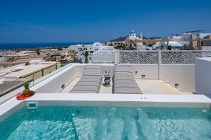 A rooftop pool with a view of the sea, white buildings, and a patterned fence. - La Madeleine Oia Suites and Caves (Santorini)