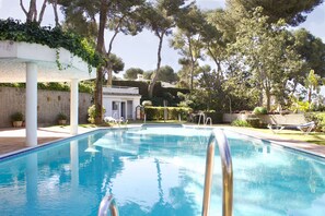 A swimming pool with clear blue water, surrounded by trees and a white building with a garden. - Newly renovated flat by the sea, south-facing terrace, sea 8 min. walking (Sitio de Calahonda)