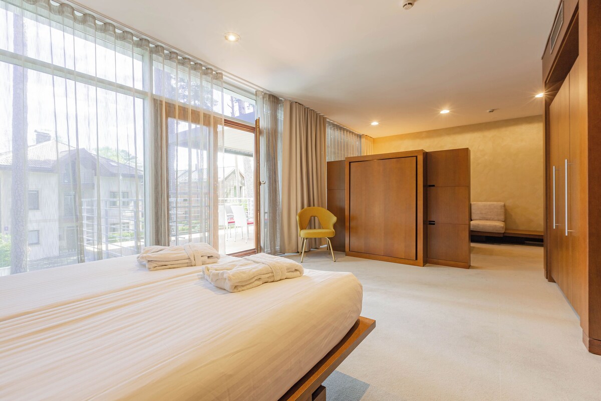 Habitación de hotel con una cama grande, una silla, un armario y vistas al exterior.