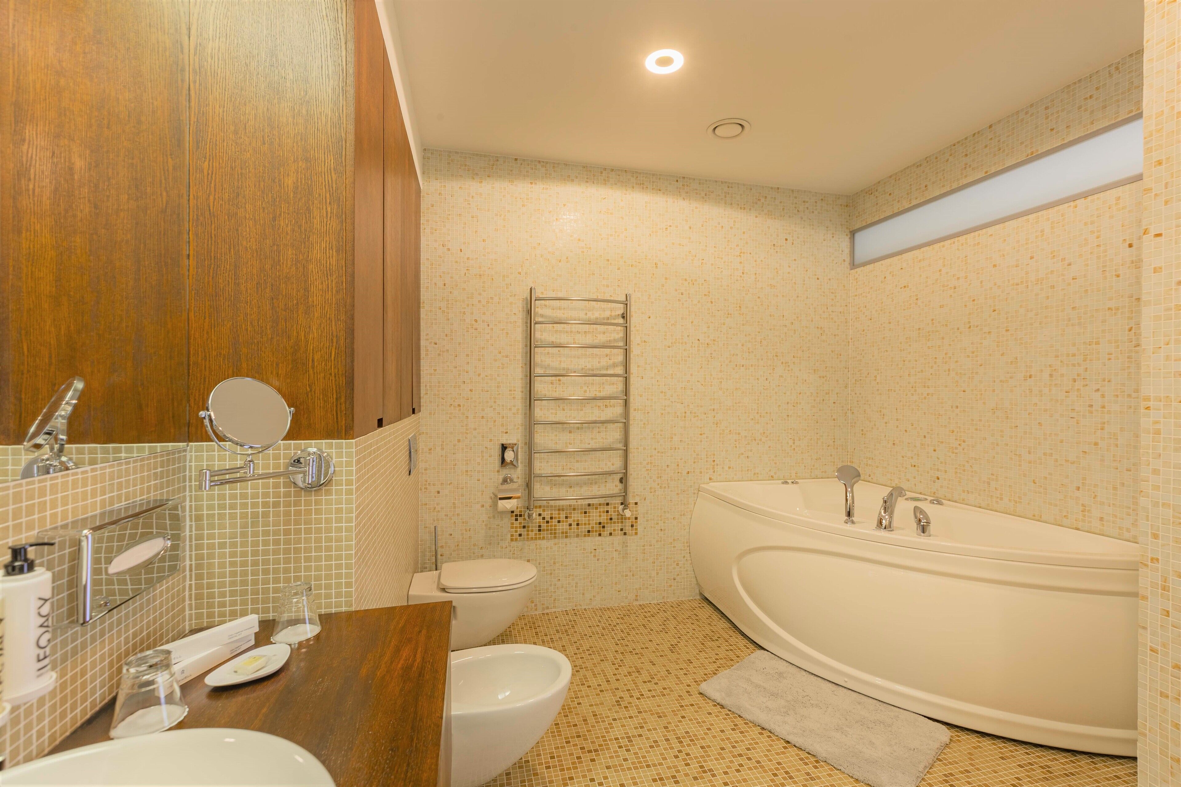 A bathroom with a wooden vanity, a sink, a toilet, and a freestanding bathtub.