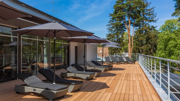 A deck with sun loungers and umbrellas, overlooking a forested area. - Rixwell Collection Seaside Hotel Jurmala (Jurmala)