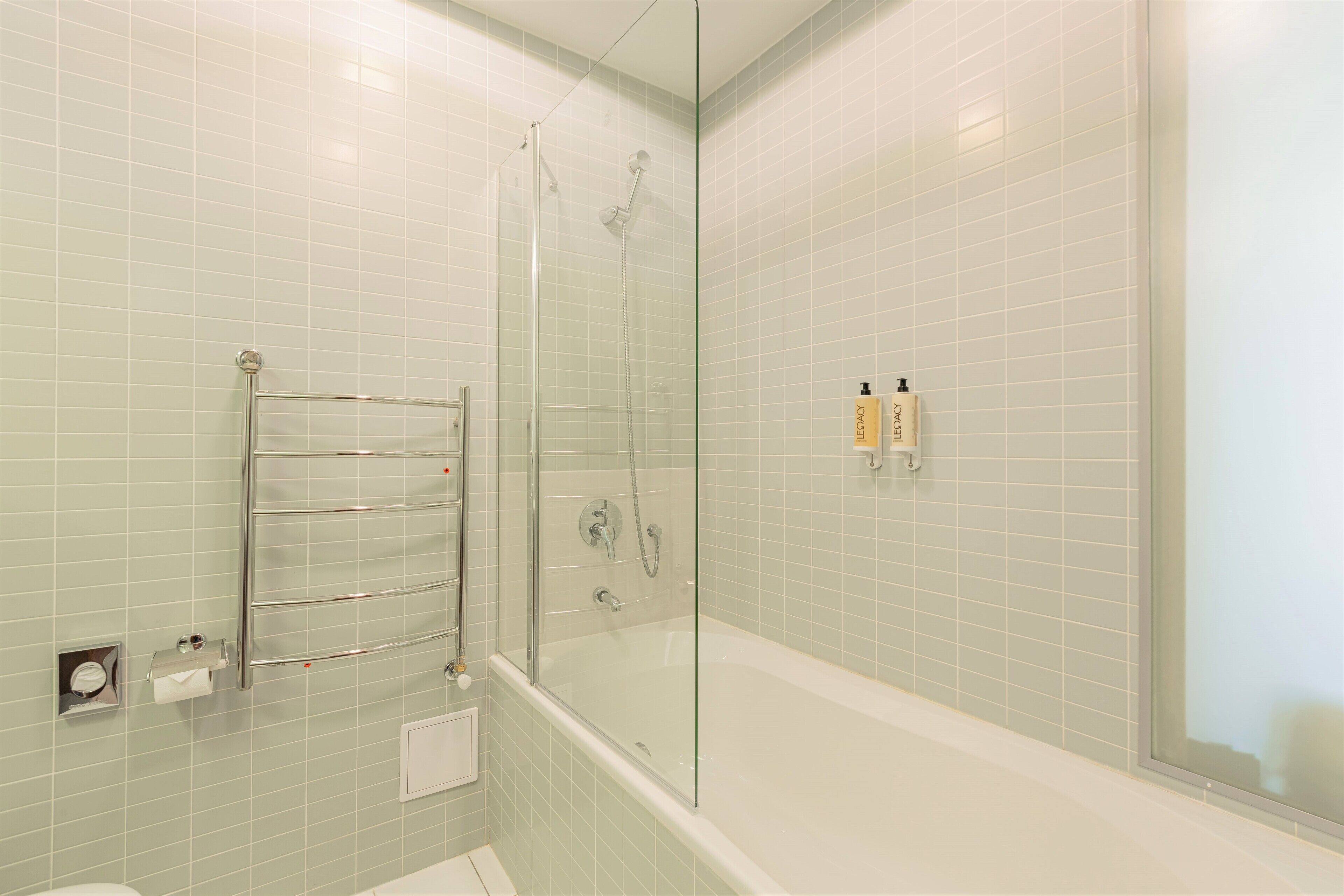 Une salle de bain moderne avec une douche à parois de verre, une baignoire en verre et un porte-serviettes.