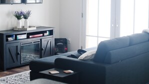 En moderne stue med en mørkegrå sofa, et fladskærms-tv monteret på væggen og et træloft.