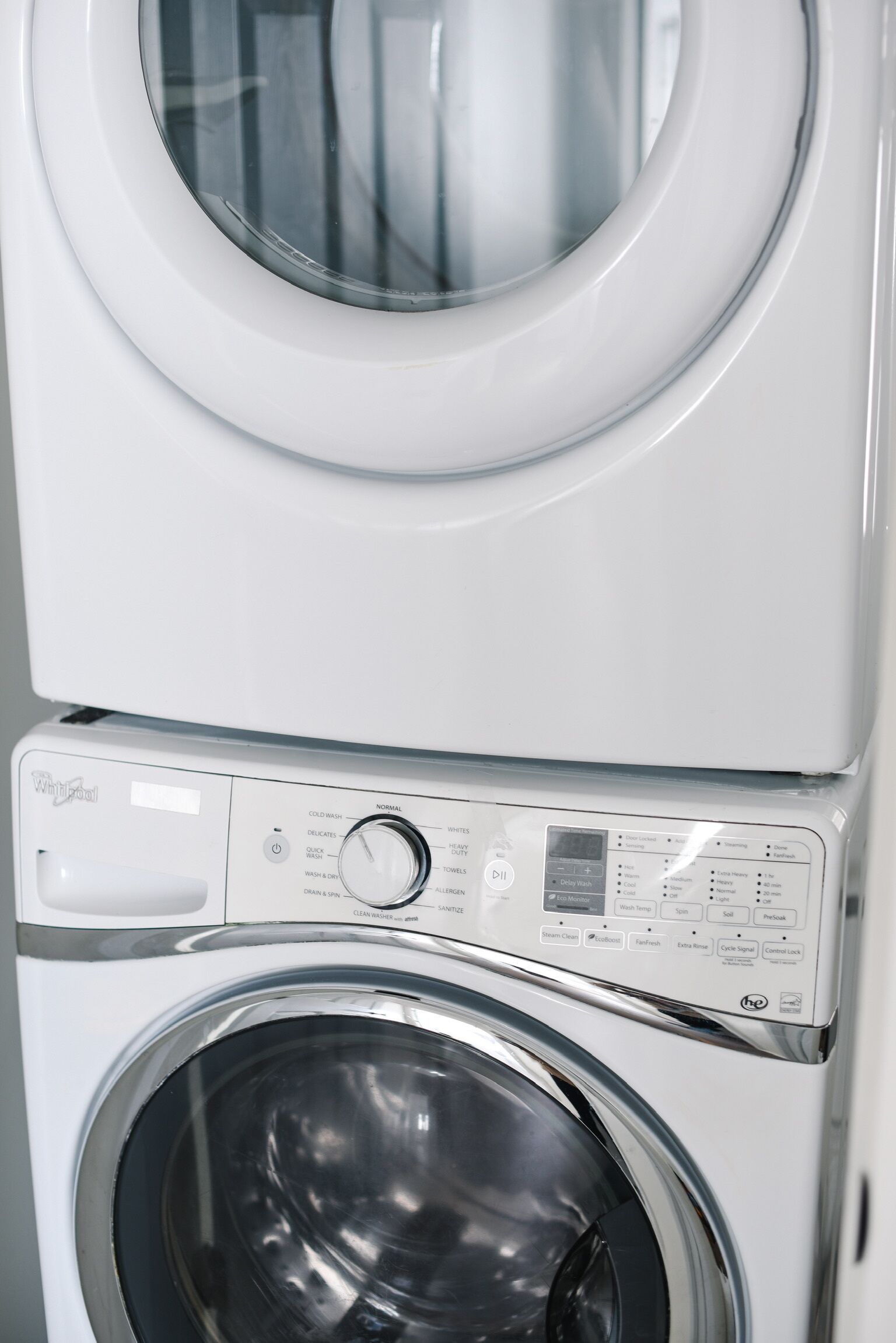 A stacked washer and dryer unit with a control panel displaying various settings.
