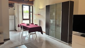 A compact kitchen with a dining area, a refrigerator, a cabinet with glass doors, and a television on a cabinet. - VERONETTA 52 (Verona)