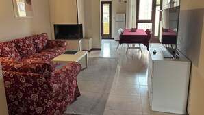 A living room with a sofa, TV, and a dining area with a table and chairs. - VERONETTA 52 (Verona)