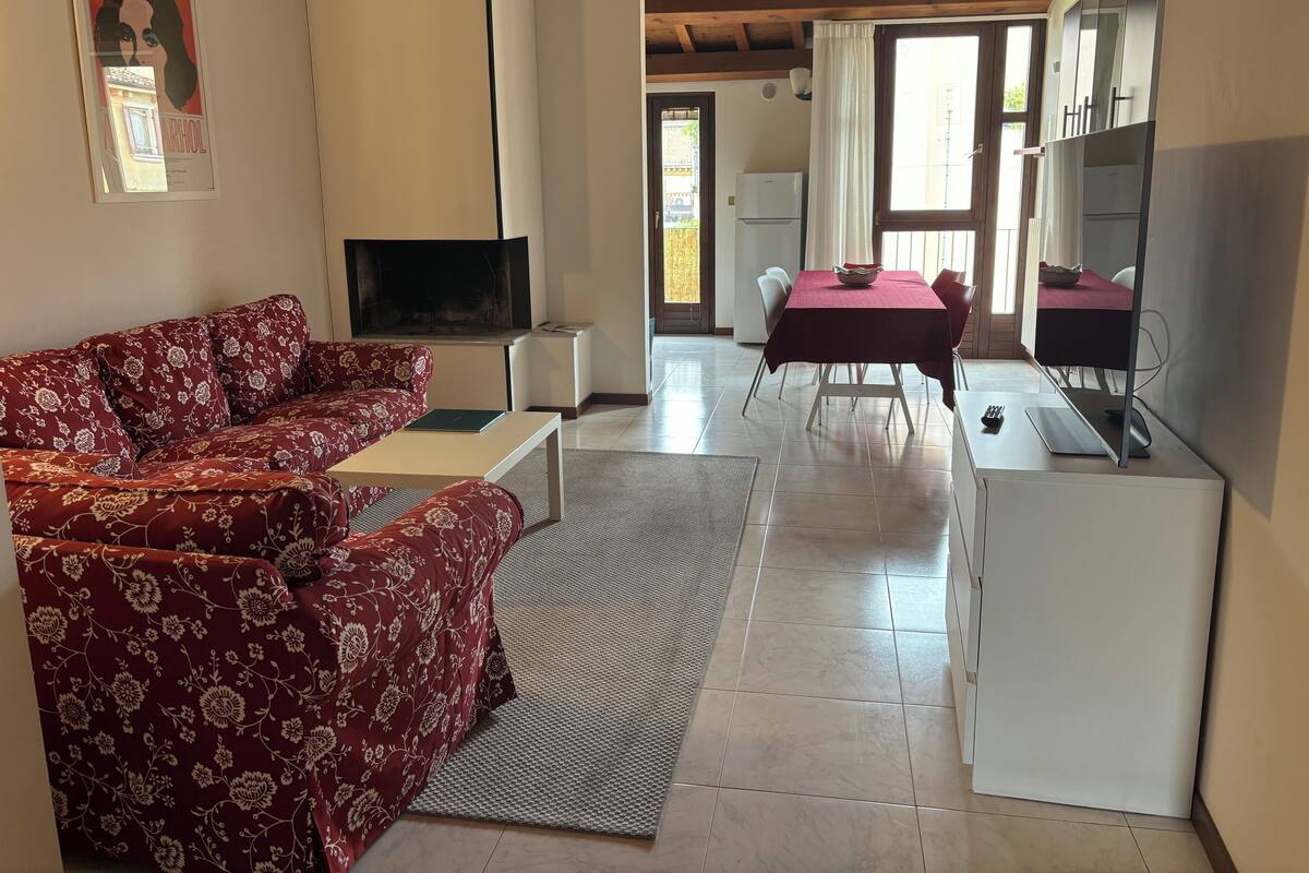 Uma sala de estar com sofá, TV e um espaço de refeições com mesa e cadeiras.