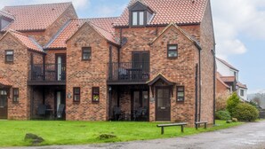 A brick building with a balcony, a door, and a bench in front. - 3 bedroom accommodation in Whitby (Whitby)