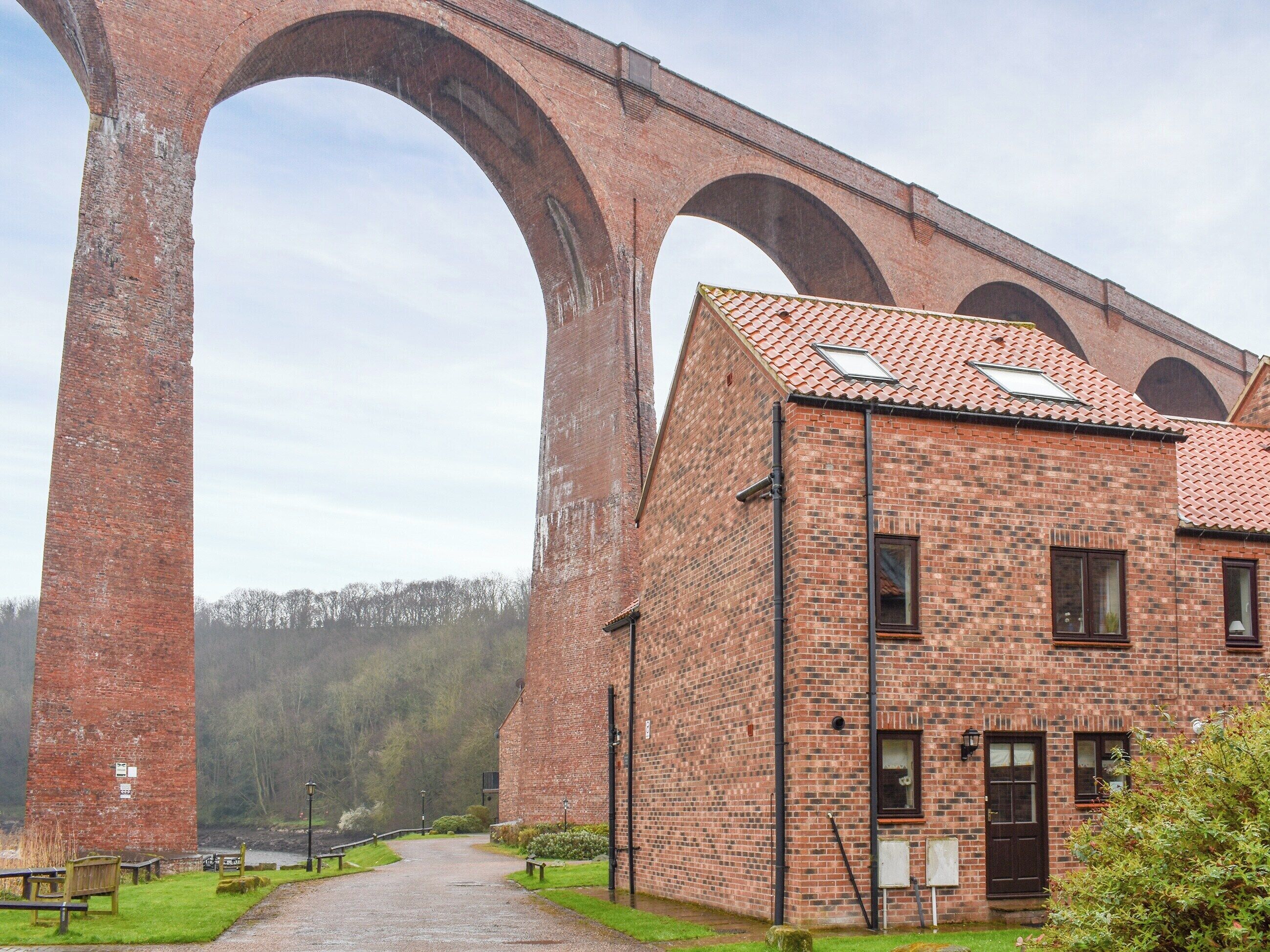 A brick building with a large arched structure in the background.