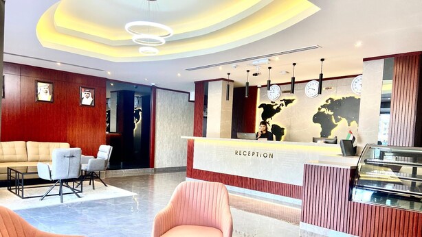 En hotellobby med modern design, med en receptionsdisk, en sittgrupp med soffor och fåtöljer samt en dekorativ vägg med en världskarta.