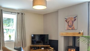 A living room with a television, sofa, fireplace, and a painting on the wall. - Terraughtie Cottage West-UK43408 (Dumfries)