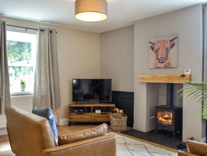 Ein Wohnzimmer mit Fernseher, Sofa, Kamin und Kunstwerken.
