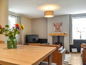 Un salon moderne avec une table en bois, un téléviseur à écran plat, une cheminée et un tableau accroché au mur.
