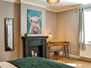Une chambre à coucher avec un lit, un bureau, une cheminée et un tableau au mur.