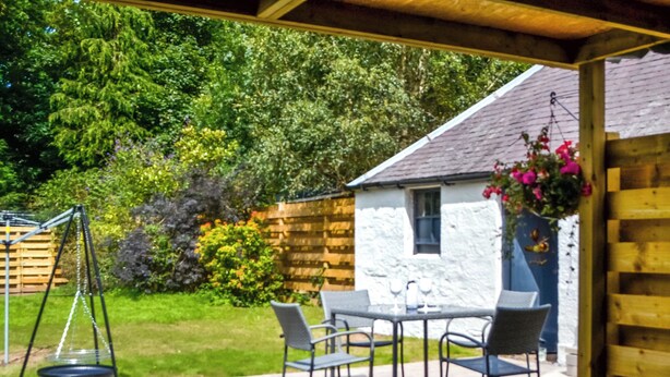 A patio with a hot tub, outdoor seating, and a swing set. - Terraughtie Cottage West-UK43408 (Dumfries)