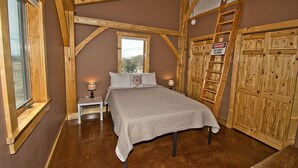 A bedroom with a bed, a nightstand, a window, a wooden ladder, and a wardrobe. - Whispering Hills Retreat (Saguache County)