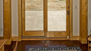 A room with a large wooden-framed arched window and a double door leading outside. - Whispering Hills Retreat (Saguache County)