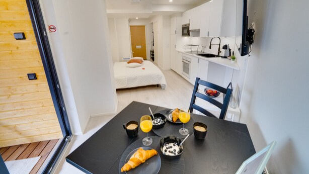Een moderne hotelkamer met een eethoek, kitchenette en een bed.
