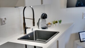 Een moderne keuken met een roestvrijstalen spoelbak, een koffieapparaat en een kleine potplant.