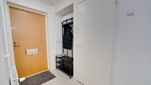 Een kamer met een houten deur, een radiator, een zwarte schapenkast en een witte garderobe.