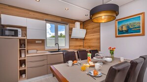 A modern kitchen with wooden cabinets, a microwave, and a dining area with a table set for breakfast.