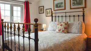 Un dormitorio con cama, ventana con cortinas e imágenes enmarcadas en la pared.