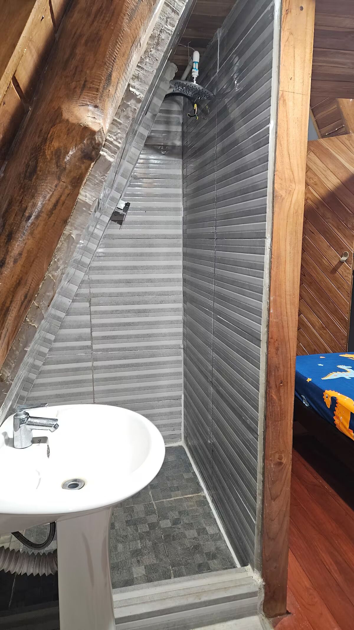 A small, enclosed shower area with a white sink and a showerhead.