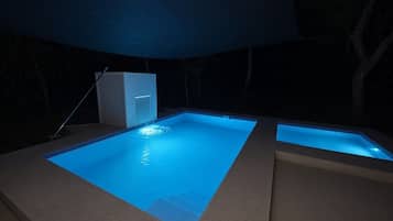 Una piscina con una cascada, rodeada por una zona cubierta.