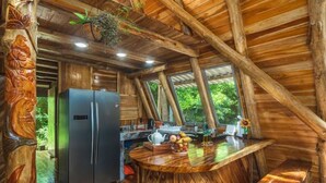 Een rustiek houten interieur met een grote koelkast, een houten eettafel en een hangplant.