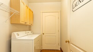 Ein Waschraum mit Waschmaschine und Trockner, Holzausbau und einer Tür mit der Aufschrift 'LAUNDRY'.