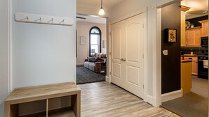 Un couloir avec un porte-manteau, un banc et une porte donnant sur un espace cuisine.